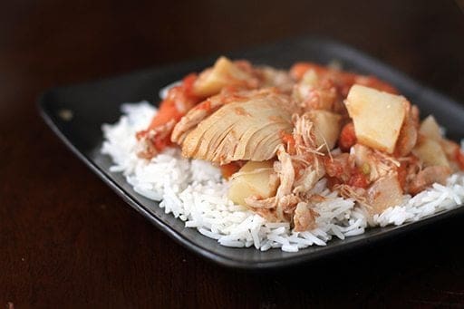 Chicken & Potato Stew on top of rice in a black plate bowl