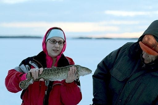 woman in red coat holding a burbot fish with two hands
