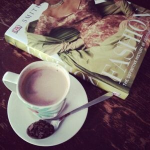 top down shot of a cup of coffee beside a fashion book