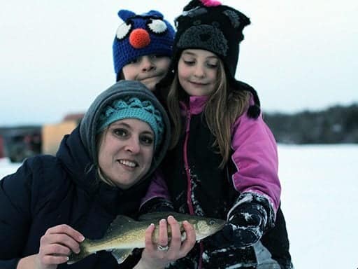 Mom holding a walleye fish together with her two kids