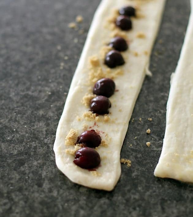 dough strip with butter, sprinkled with brown sugar and cherry halves