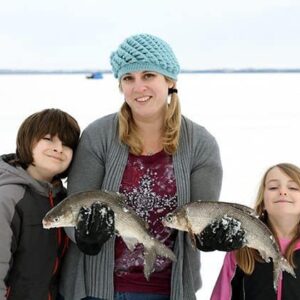 mom in the middle of her two young kids holding two fishes in each hand
