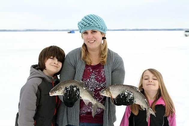 family fishing, mother holding two fishes while her kids on each side beside her