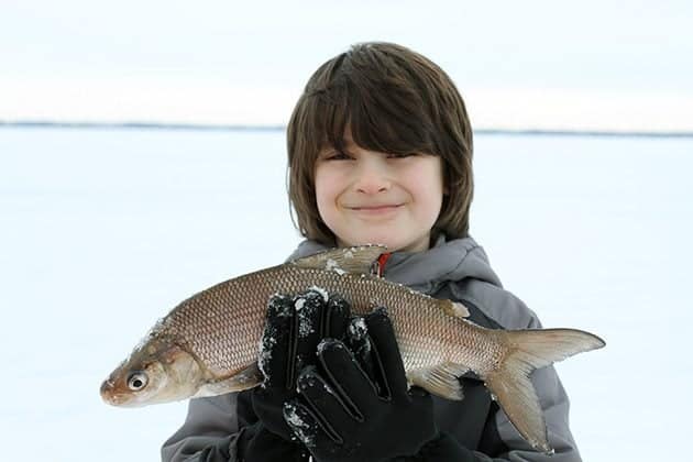 young boy holding a big whitefish with his both hands