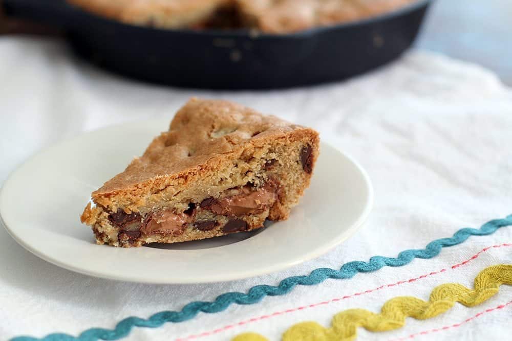 A slice of Mars Bar Stuffed Skillet Chocolate Chip Cookie in a White Plate