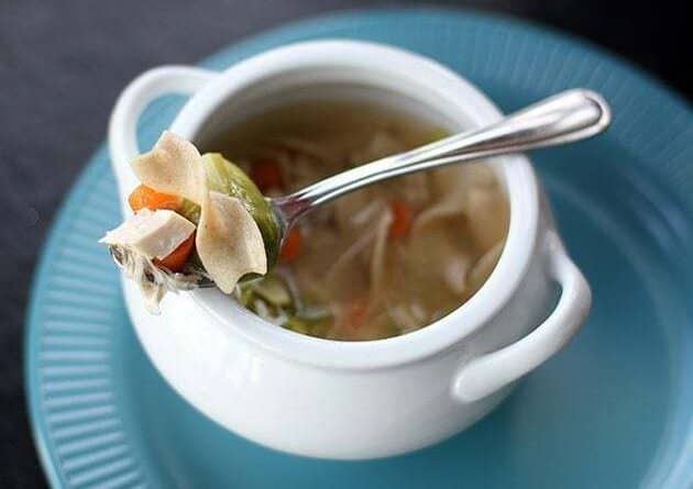 Cheater Chicken Soup in a white bowl with handle, a spoon with vegetables and chopped chicken on top of the bowl