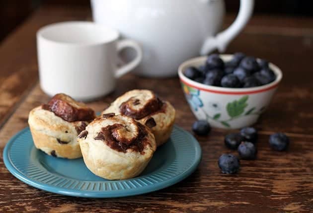 Chocolate cream cheese breakfast biscuits in a blue plate with some fresh blueberries in a cup