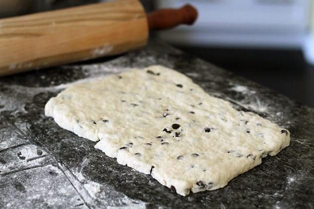 rolled out dough with chocolate chips, a rolling pin at the side