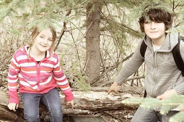 young girl and boy sitting in a log of tree