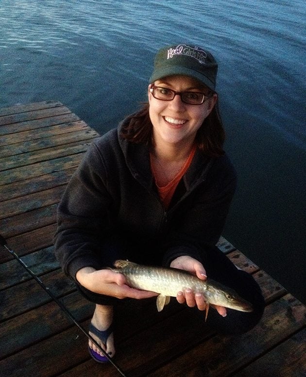 woman wearing cap and glasses holding baby Northern Pike 