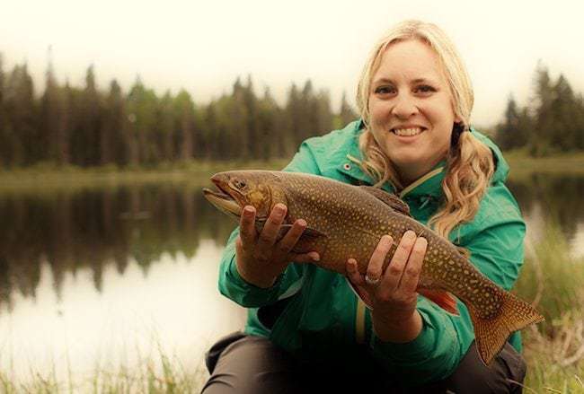 woman holding brook trout catch from fishing 