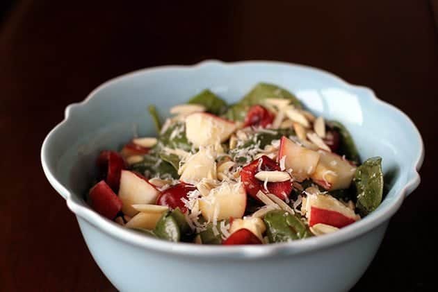 Close up of Apples N' Cherries Spinach Salad in a blue Pyrex bowl