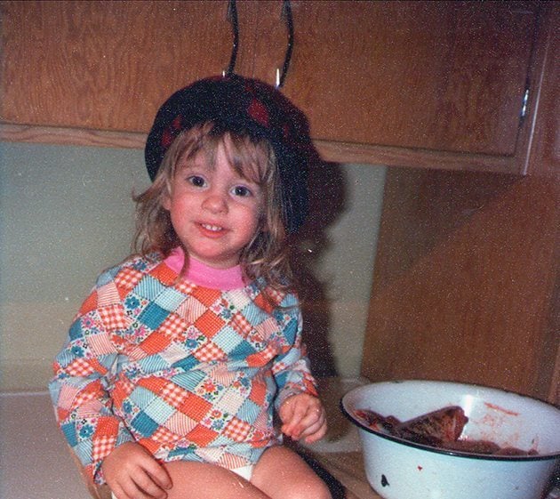 cute little girl sitting in the table with bowl of fish beside her