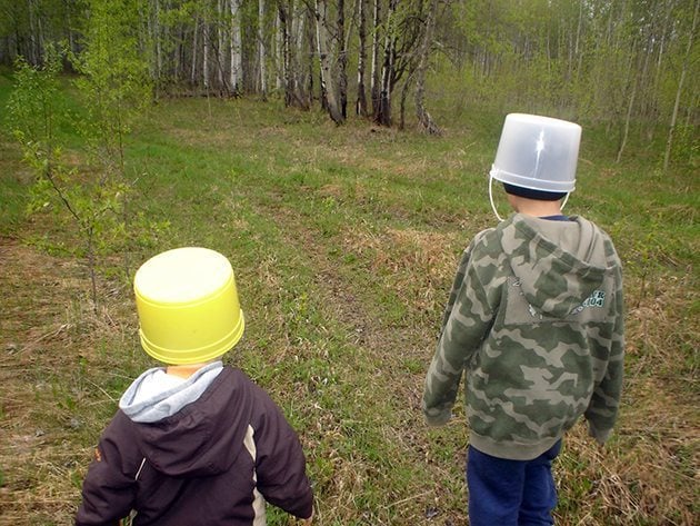 two little boys walking while wearing the buckets in their heads