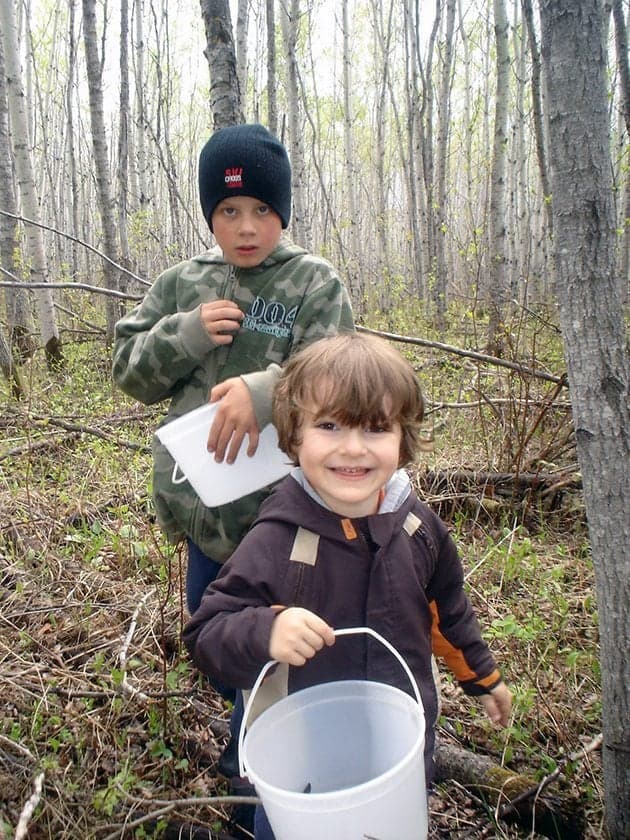 two boys in the forest holding white buckets