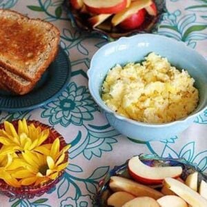 top down shot of scrambled eggs, whole grain toast and sliced organic gala apples in the table for Sunday breakfast
