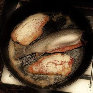 cleaned and sliced brook trout in skillet with butter
