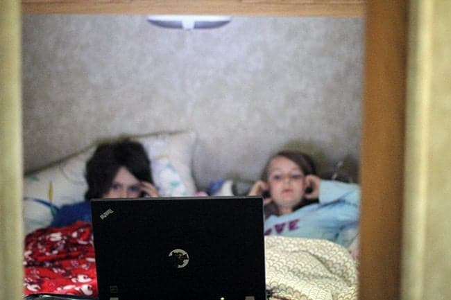 kids in front of master bedroom with laptop watching a movie