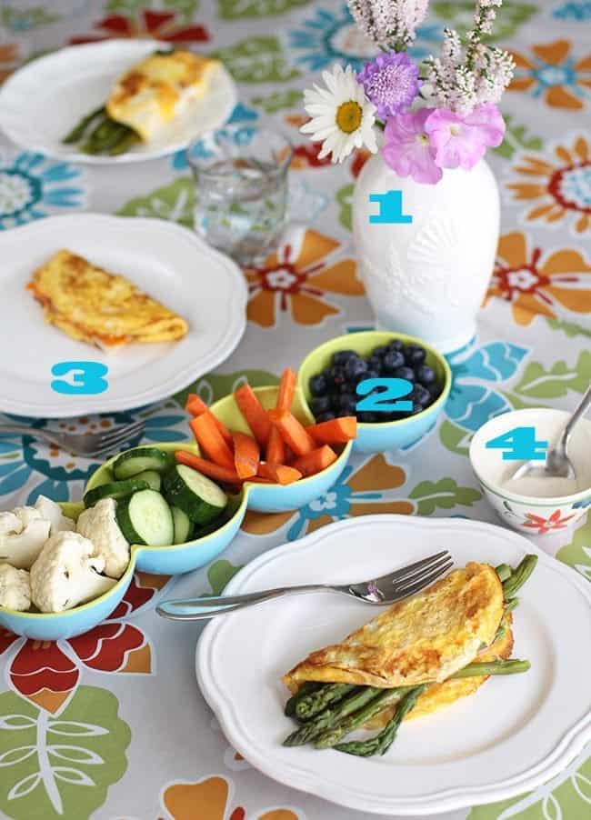 plates with asparagus and cheese omelettes, serving dishes with vegetables and blueberries on the table