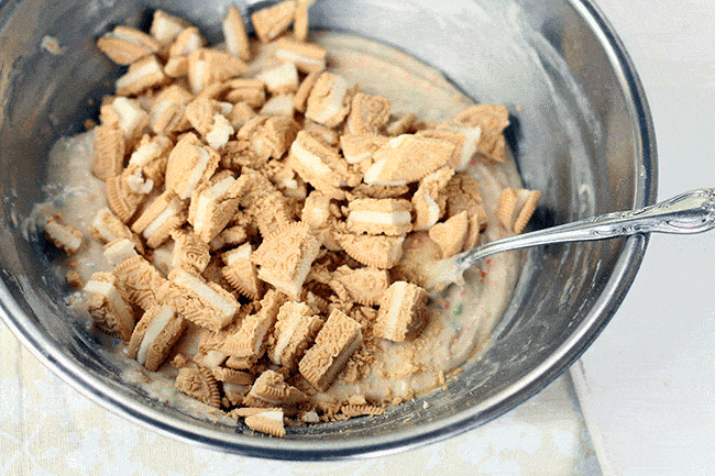adding chopped up Golden Oreos to cake mix in a mixing bowl