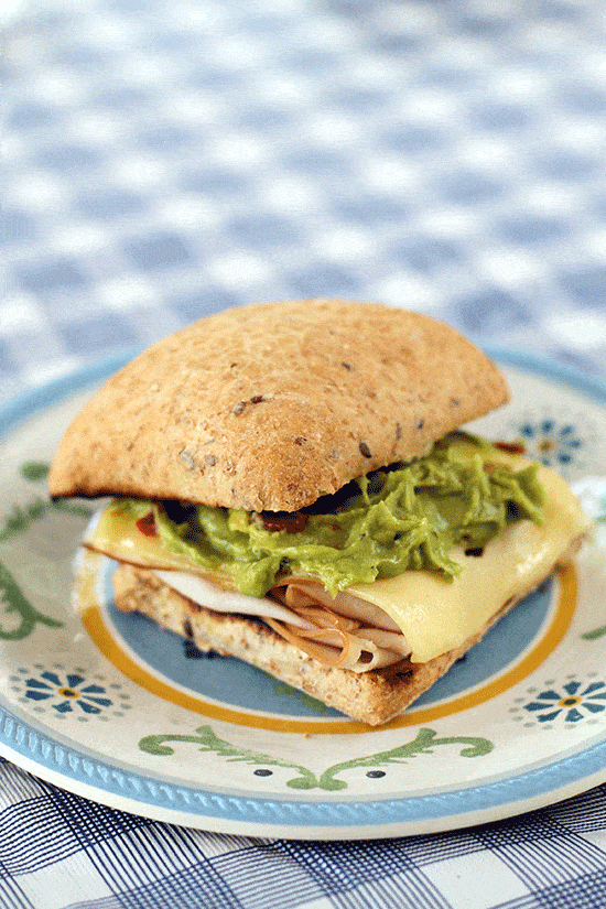 toasted buns with turkey at the bottom, top with Swiss cheese, guacamole and mastard