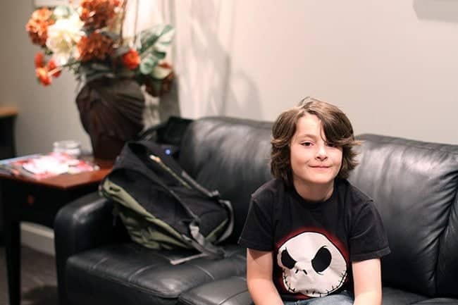 young boy in black shirt sitting in the black couch