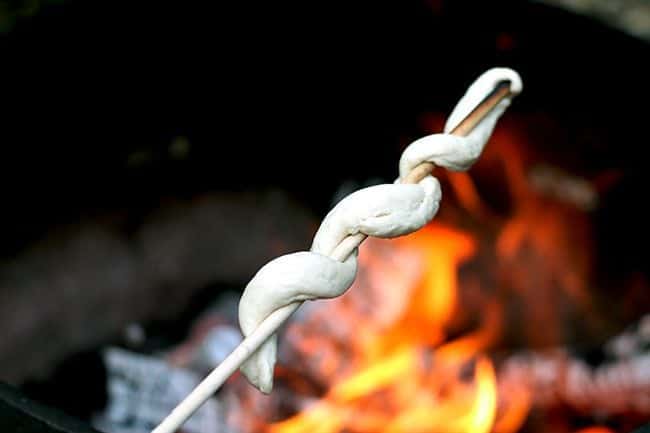 close up of wrapped biscuit dough over a campfire