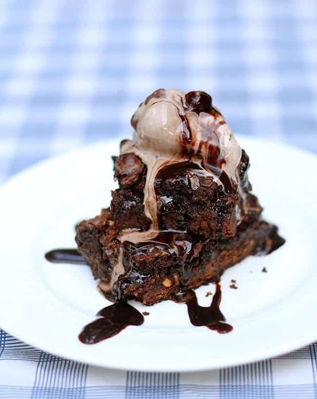 white plate with stack of chocolate chip cookie bars topped with ice cream