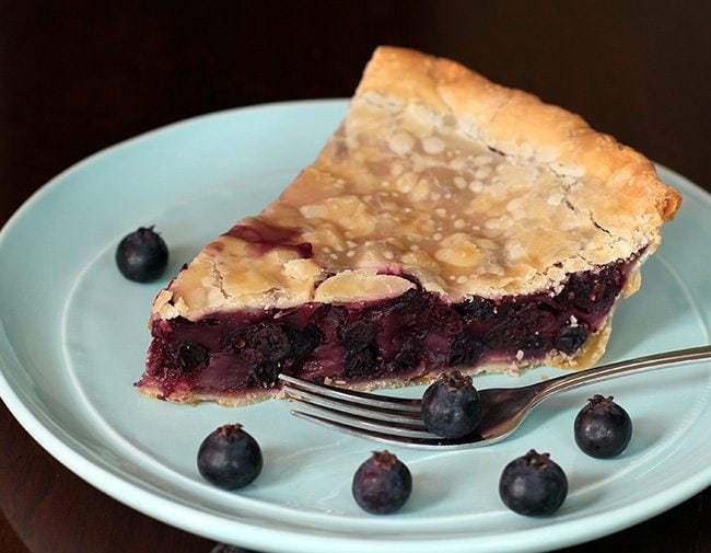 mint green plate with a slice of Saskatoon Cream pie and some fresh saskatoon berries