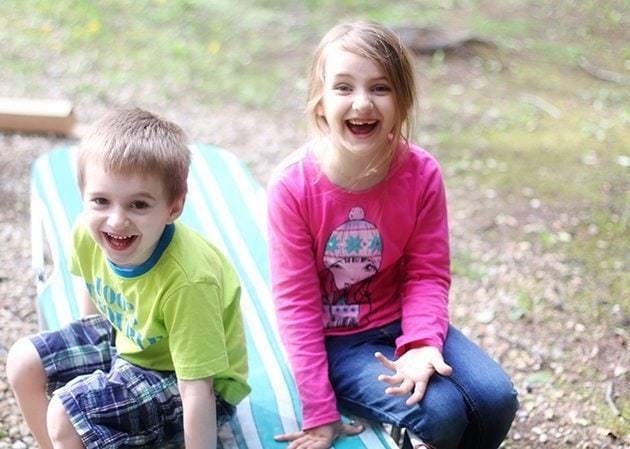 little boy wearing lime colored shirt and a little girl wearing pink shirt sitting in the bench