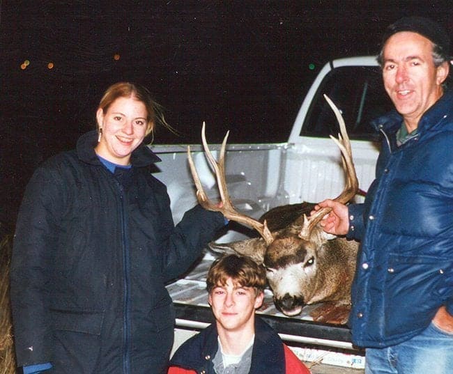 hunters holding at the deer's antlers while its in the car