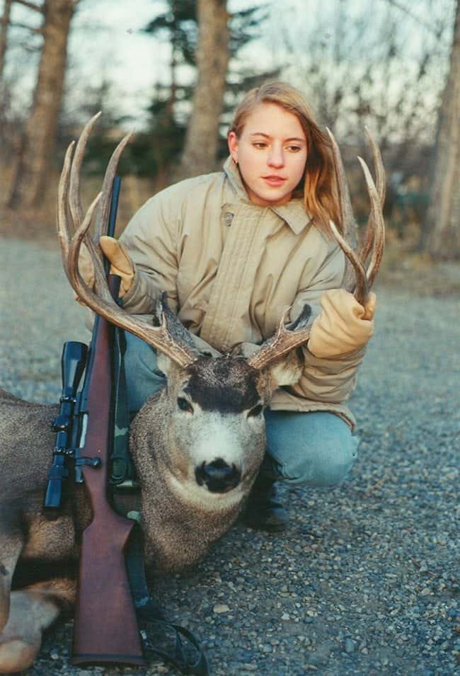 lady holding at the deer's antlers while sitting