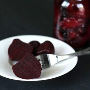 slices of pickled beets in a white small plate with a fork