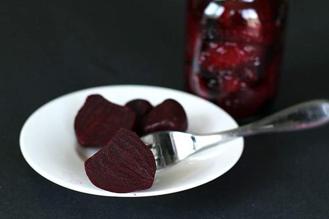 pieces of Pickled Beets in a white plate and on the jar at the back
