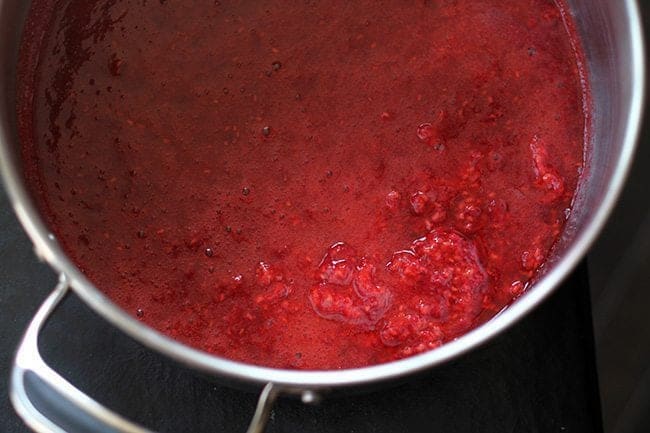 crushed raspberries in a large pot ready to be cook