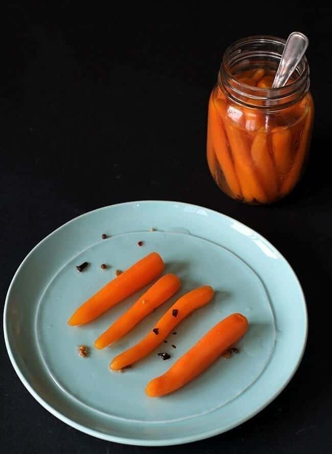 close up of Sweet Pickled Carrots in a plate and on a canning jar with spoon inside