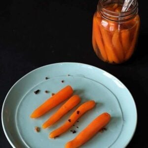 close up of Sweet Pickled Carrots in a plate and on a canning jar with spoon inside