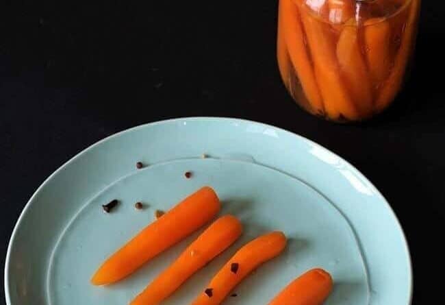 close up of Sweet Pickled Carrots in a plate and on a canning jar with spoon inside