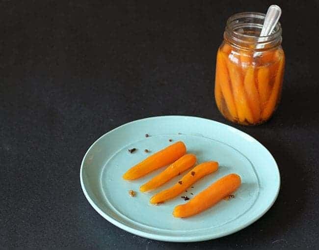 Sweet Pickled Carrots in a plate and on a canning jar with spoon inside