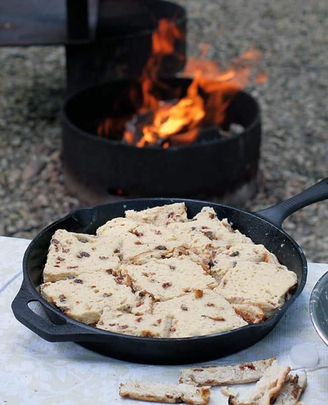 skillet filled with raisin bread with fire from BBQ on background