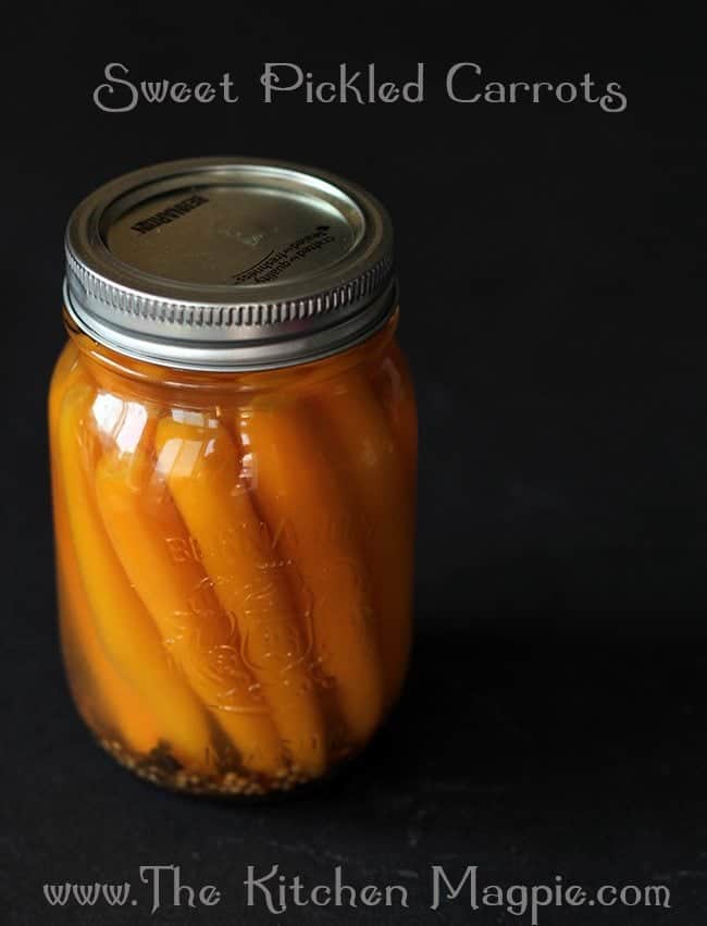 close up of sweet Pickled Carrots in a canning jar with pickling liquid in a dark background