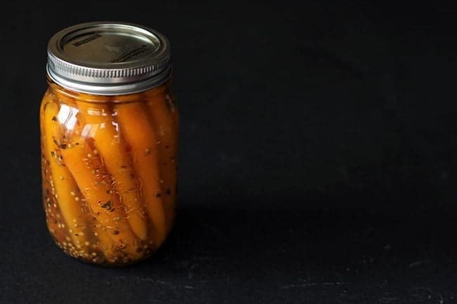 Pickled Carrots in a canning jar with pickling liquid in a dark background