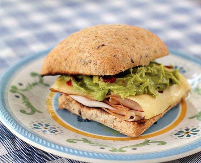 Simple Turkey, Swiss & Guacamole Toasted Sandwich on small plate with prints