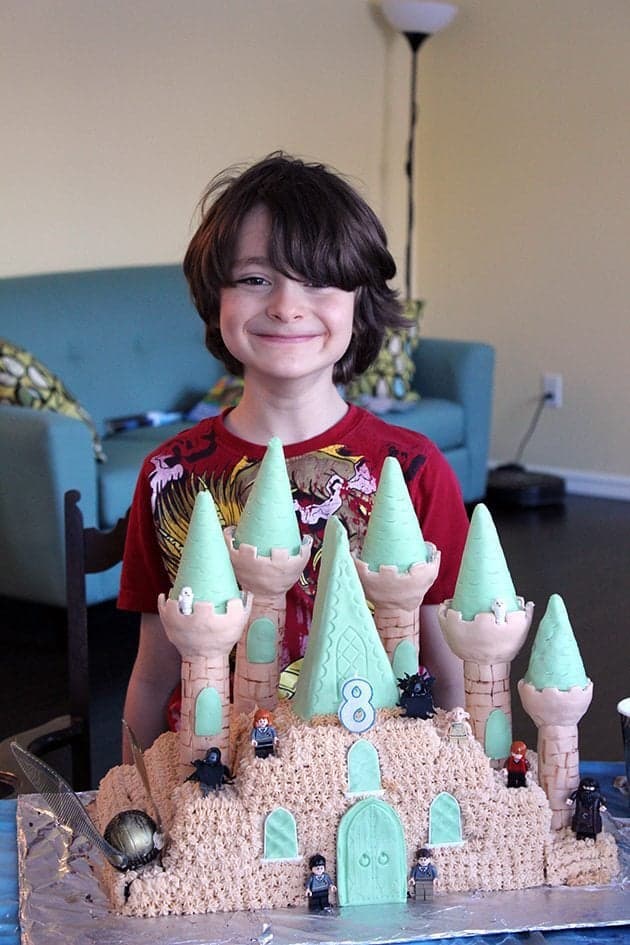 Hogwarts cake in front of a boy wearing red shirt