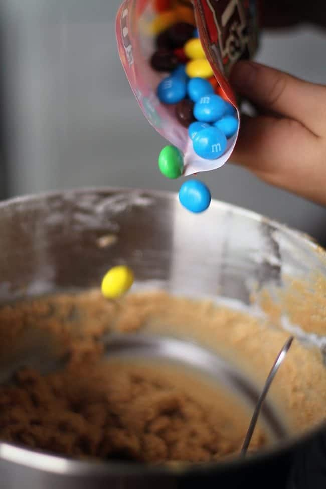 adding bright-colored M&M's to peanut butter cookie dough