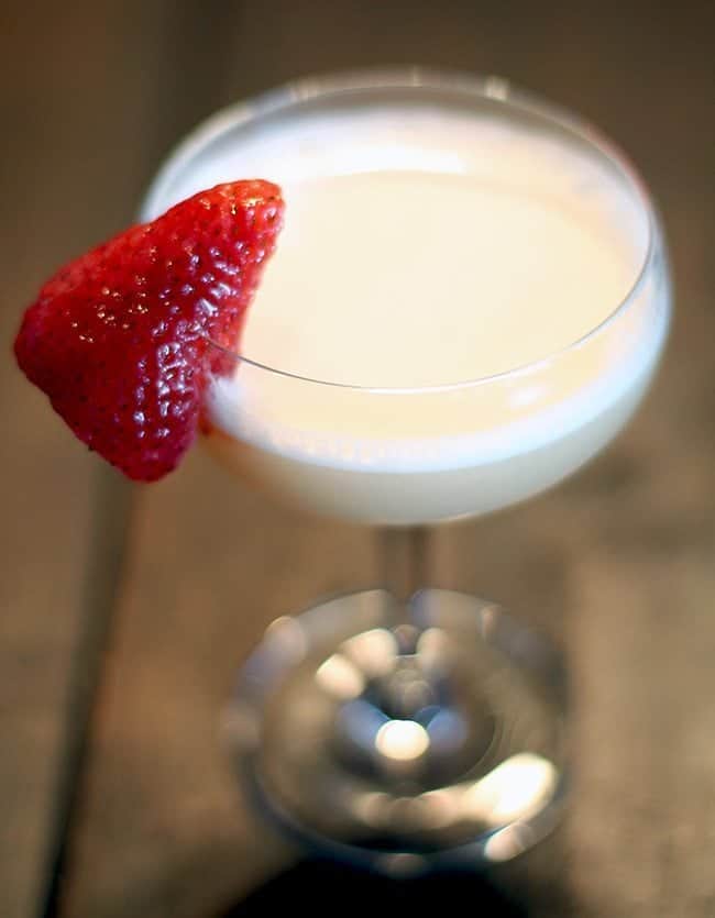 a glass of Clover Club cocktail garnish with fresh strawberry