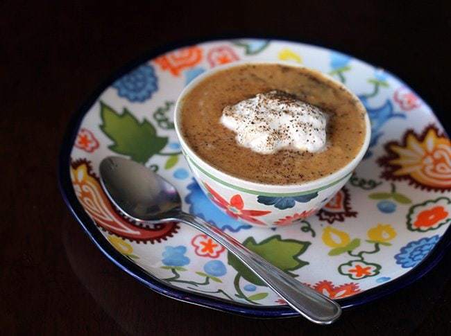 a bowl of Pumpkin Soup topped with whipping cream, sprinkled with pepper and salt