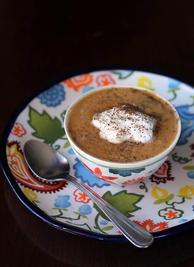 a bowl of Pumpkin Soup topped with whipping cream, sprinkled with pepper and salt