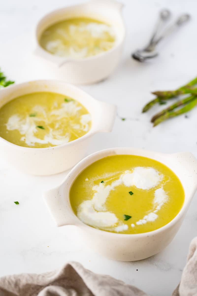 three white bowls filled with cream of asparagus soup 