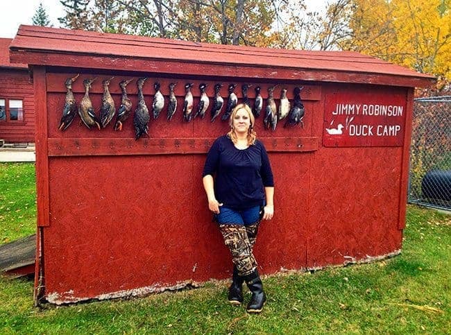woman standing in front of requisite duck wall where fallen ducks are hanging